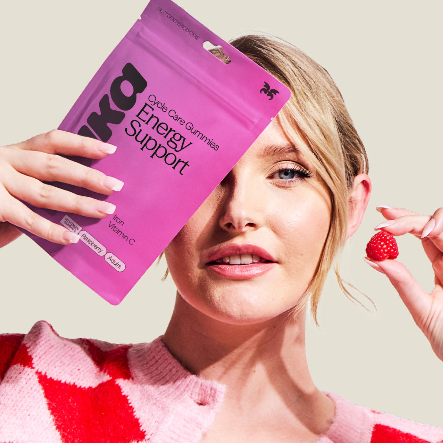 WUKA adult iron support gummies held by woman smiling with raspberry gummy in hand – energy and fatigue support supplement.