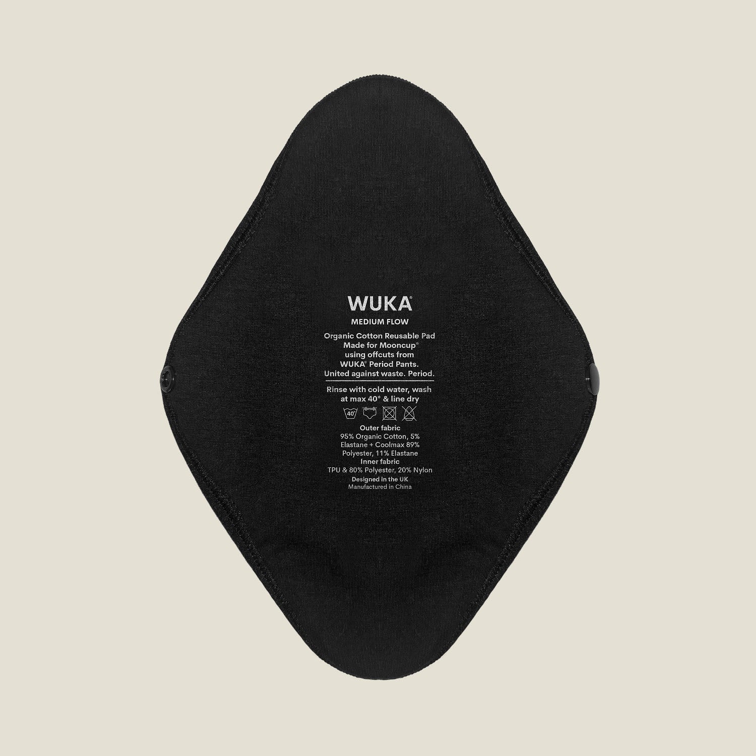 Close-up of WUKA x Mooncup reusable period pad showing organic cotton outer side with printed care instructions for medium flow.