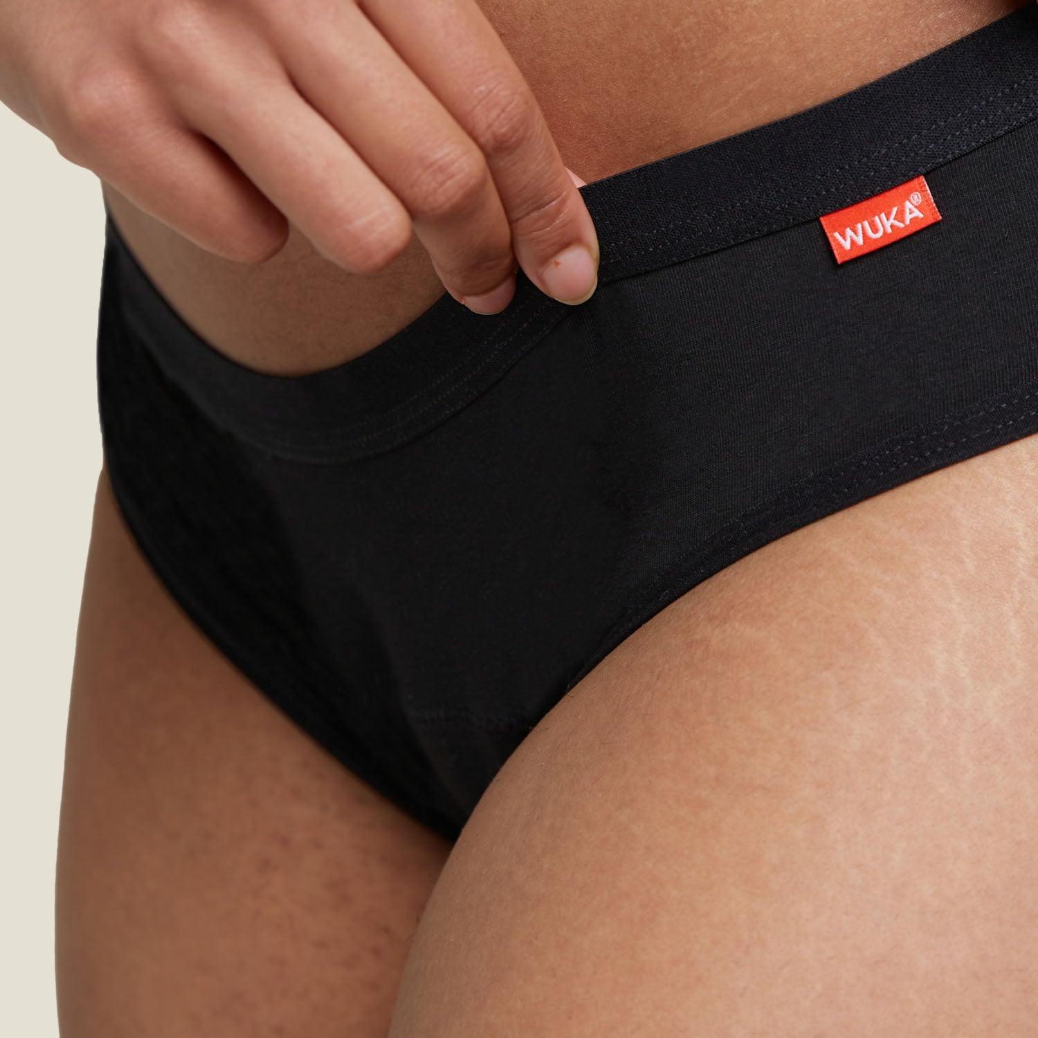 Detail shot of WUKA Basics™ Hipster Period Pants waistband with logo tag, illustrating durable stitching and fabric.