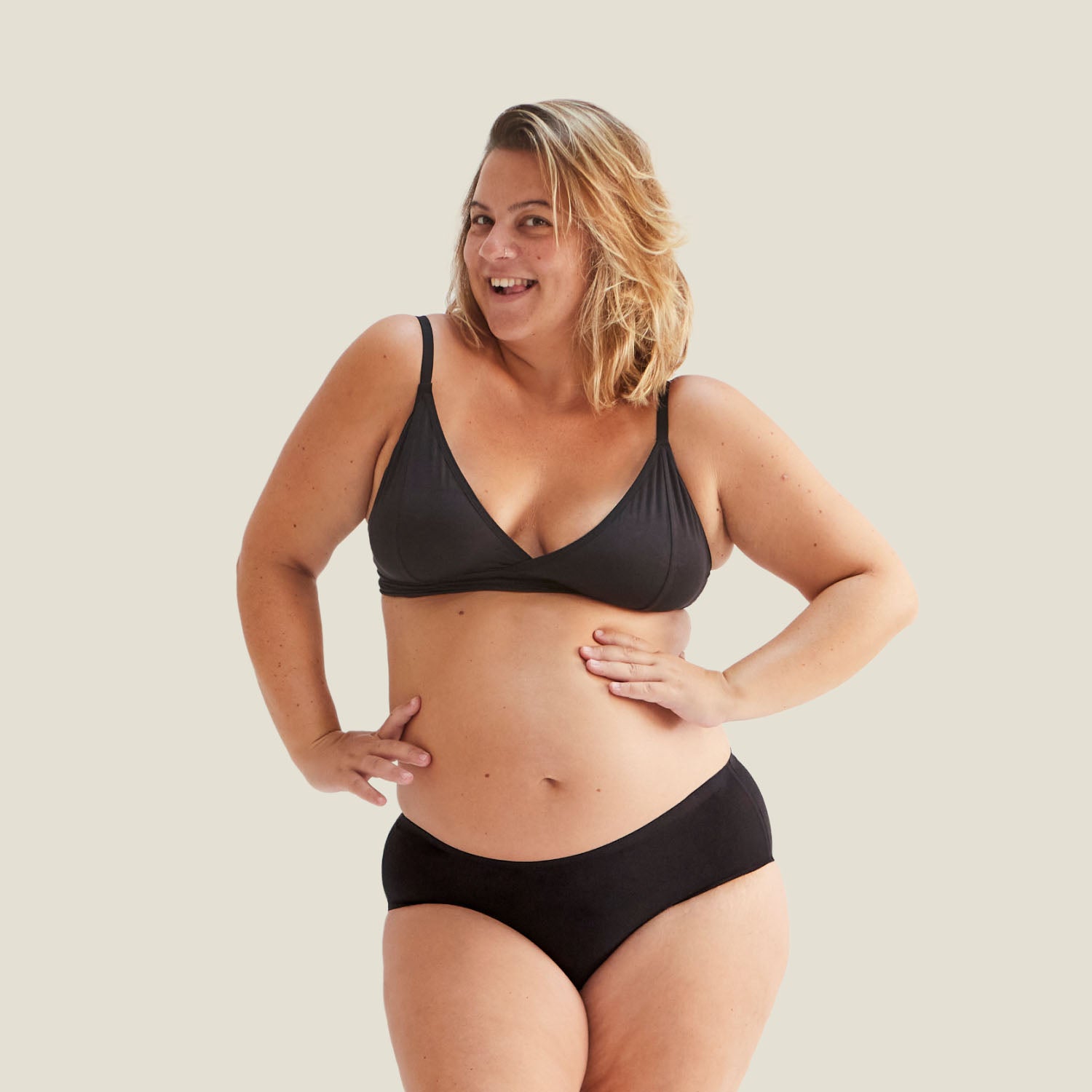 Pregnant model wearing Drytech™ incontinence midi brief in black for light leaks, smiling and posing confidently in full-length front view.