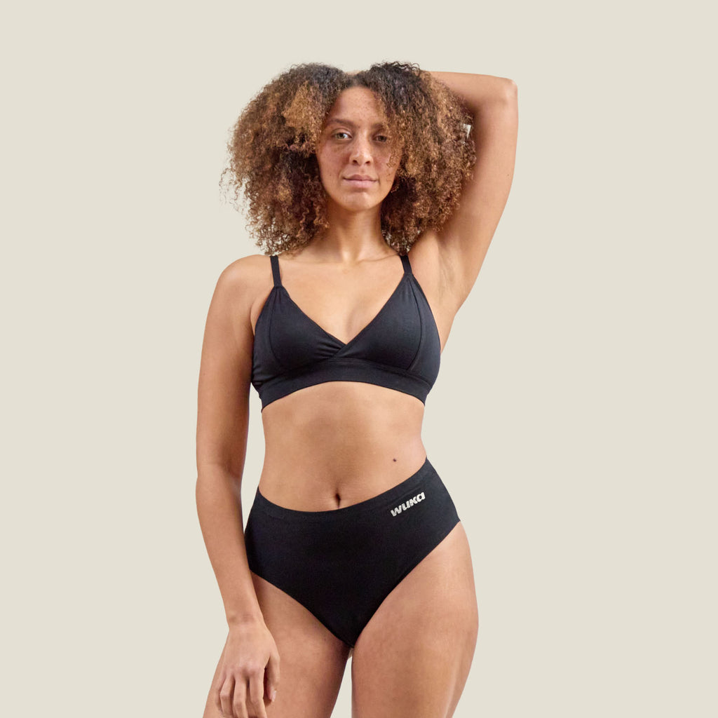 Front view of a model wearing WUKA Stretch Cotton Midi Brief for heavy flow in black, designed for 12-hour leak protection and maximum comfort.
