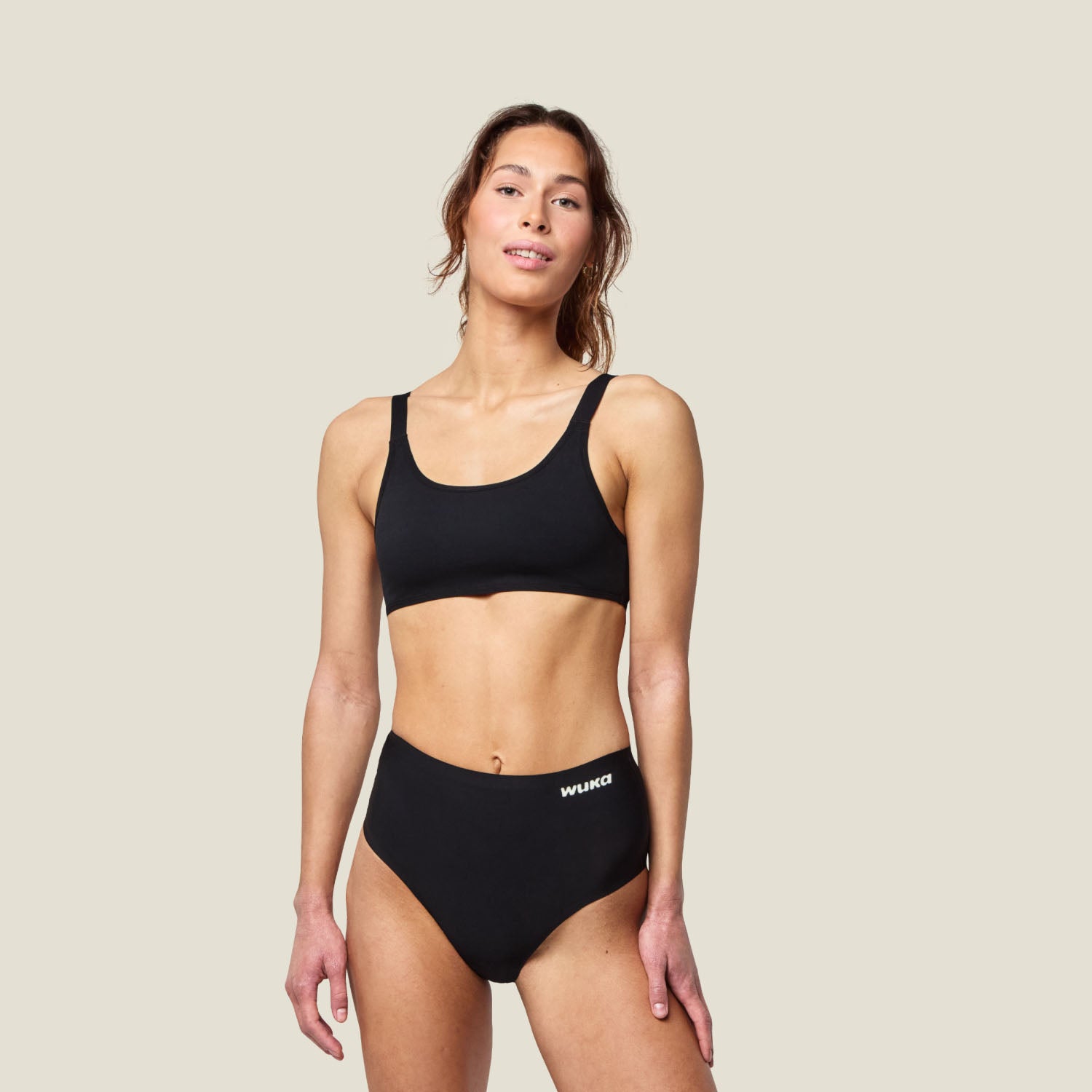 Model wearing WUKA Stretch™ Midi Brief period underwear for heavy flow with a black crop top, showcasing full-length front view.