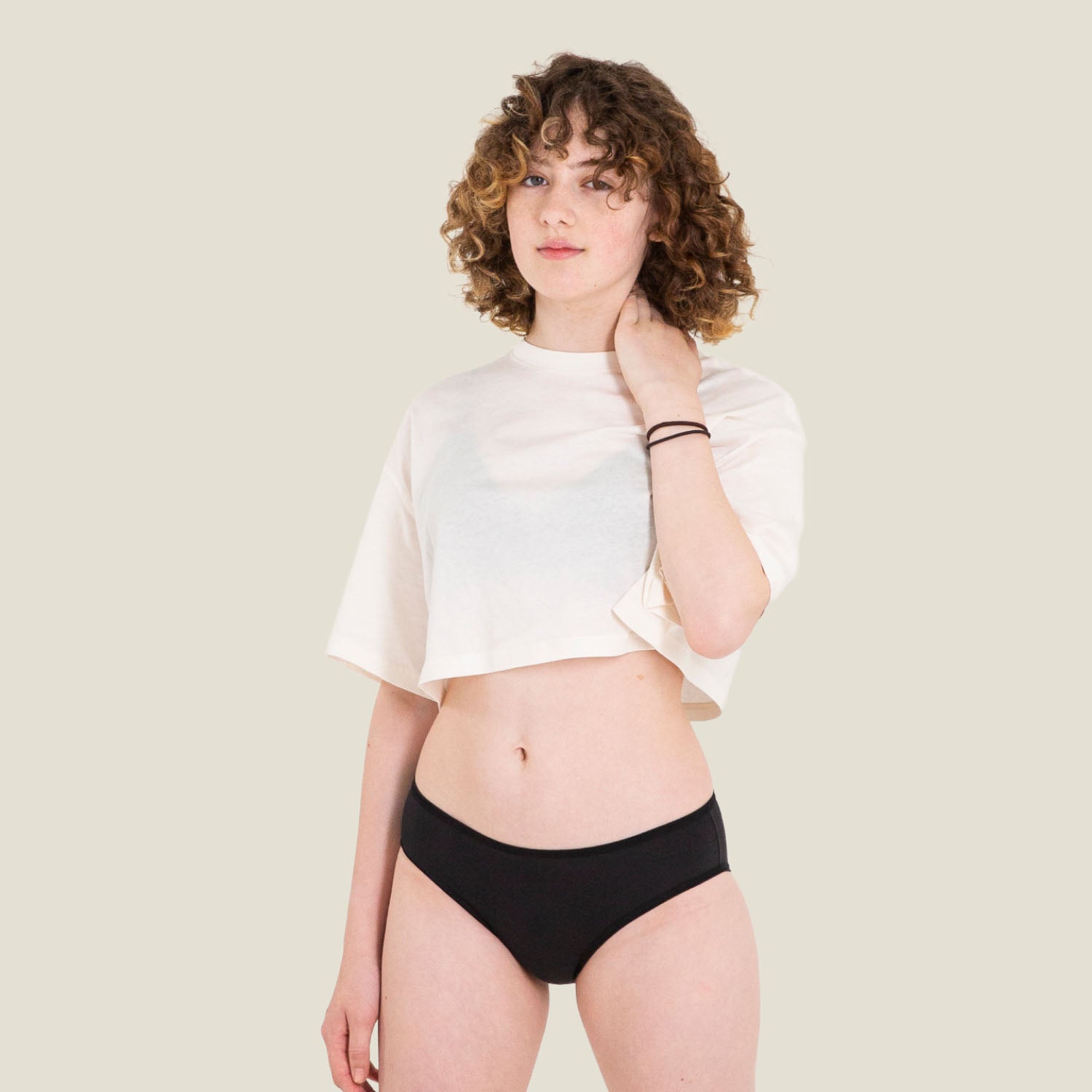Teen model wearing WUKA Teen Swim Bikini Brief in black, offering light flow period protection for confident swimming without pads or tampons.