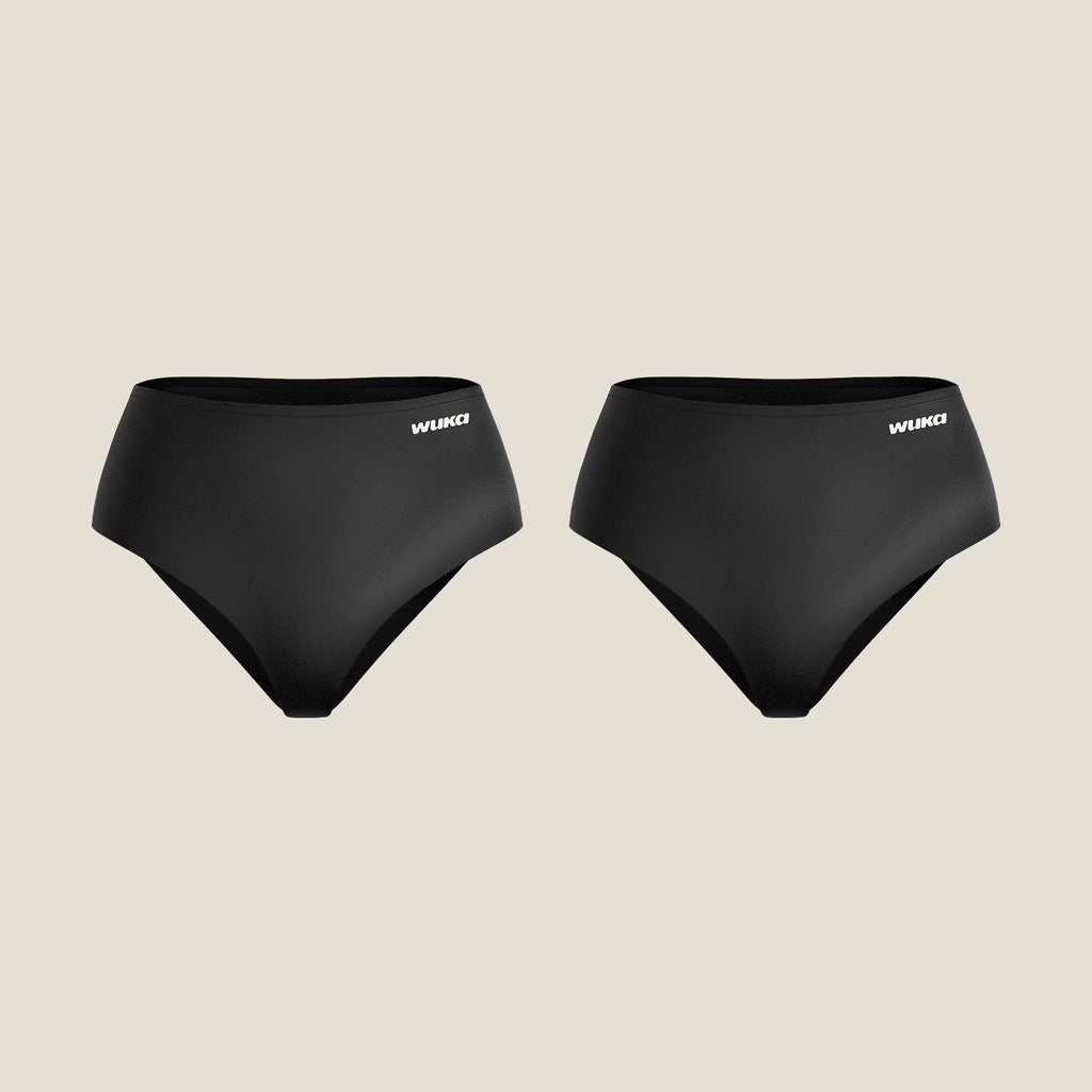 Two pairs of WUKA Stretch Seamless Midi Brief Period Pants for heavy flow in black, laid flat against a neutral background, showcasing sleek, high-leg, seamless design and front logo placement.