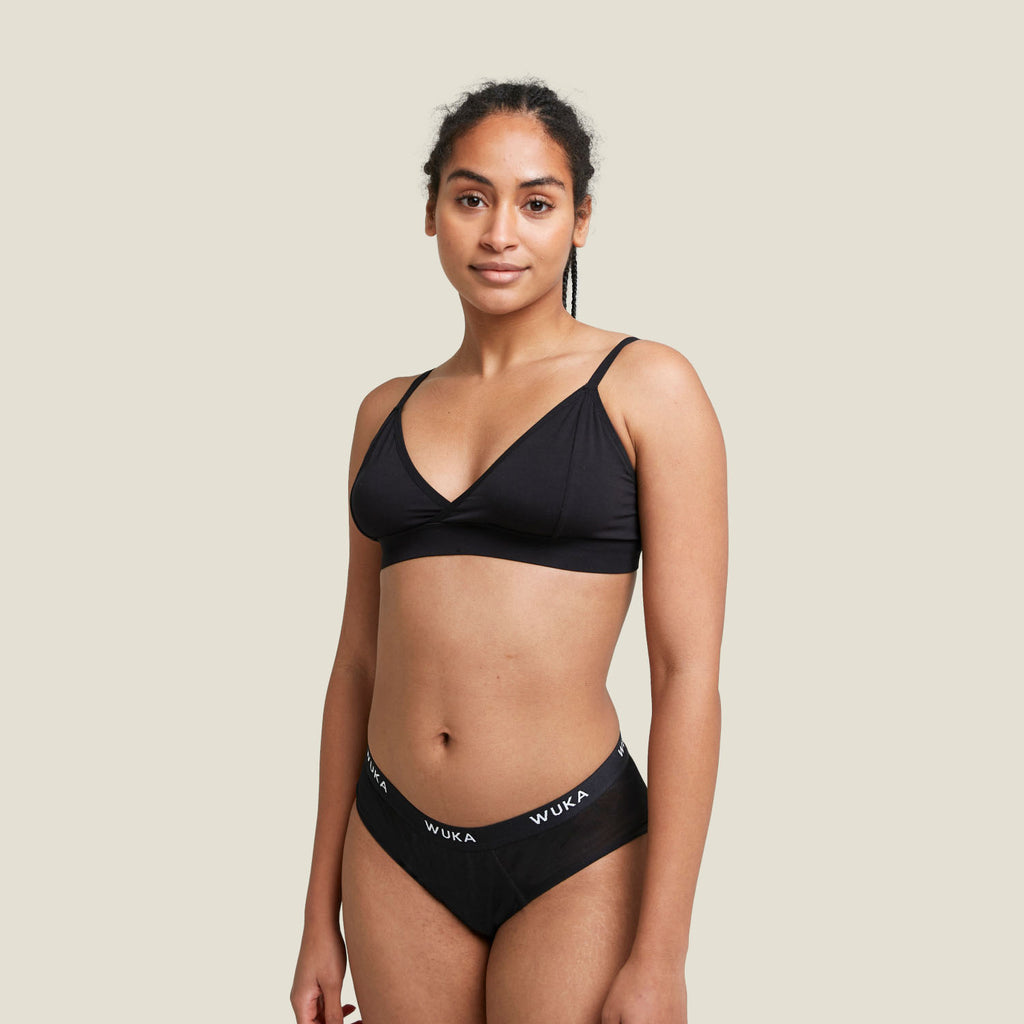 Model wearing WUKA Ultimate™ Midi Brief in black, designed for heavy overnight flow protection with a comfortable fit and soft waistband.