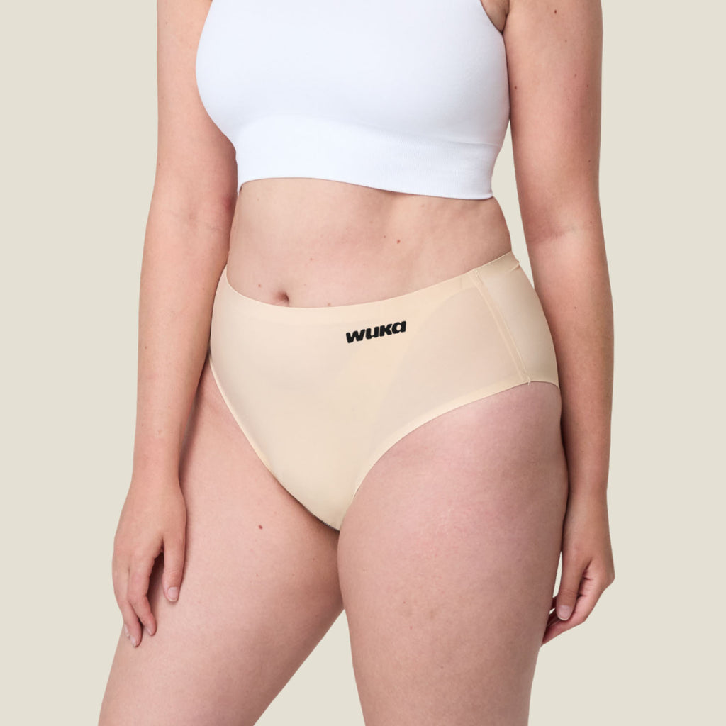 Plus-size model wearing WUKA Stretch Seamless Midi Brief in Light Nude for heavy flow, leak-proof period underwear with stretch fit, sustainable and comfortable.
