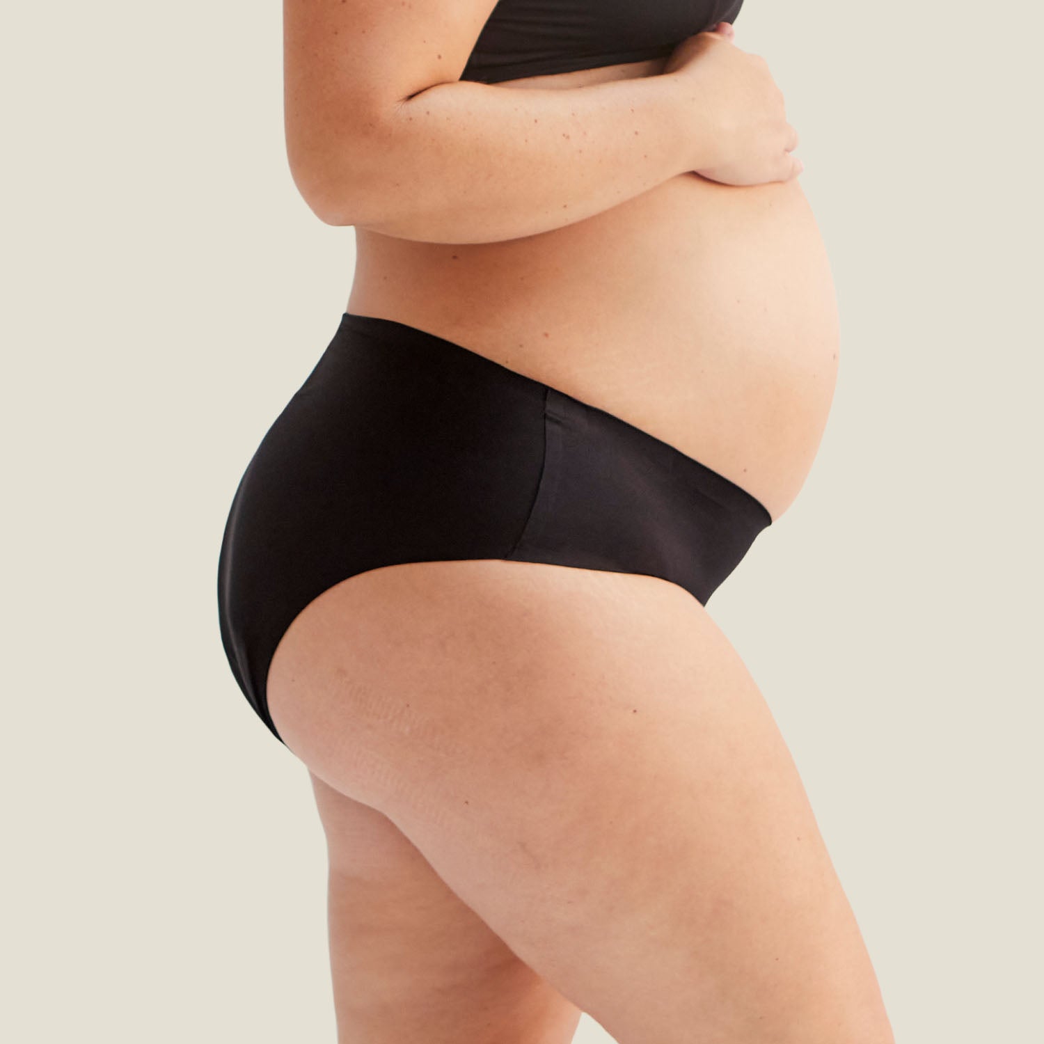 Side profile of black Drytech™ incontinence midi brief, highlighting stretchable and smooth waistband fit on pregnant model.